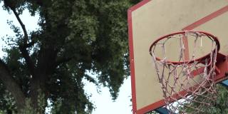 在公园的街道球场上，橙色篮球击中篮筐的特写。击中目标。达到的目标