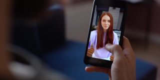 特写的男人有视频聊天通过手机享受谈话红发女友从客厅。