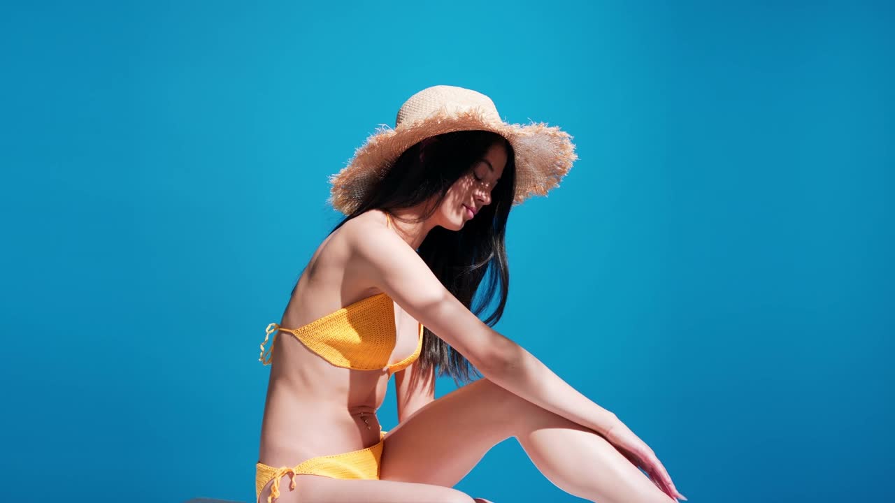 一位年轻的亚洲女性在腿上涂防晒霜，享受阳光