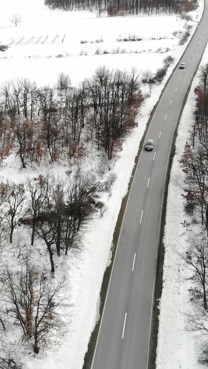 冬天的风景。鸟瞰图的道路在冬季与车辆。冰冻的冬天森林