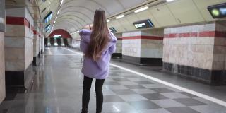 地铁里的美女模特穿着优雅的紫色合成皮草大衣慢镜头走着。女性奢华的化妆，长发和时尚的服装