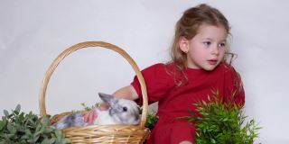女孩和兔子在草篮子里。复活节游戏儿童和宠物。动物在家里。