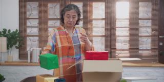 亚洲高级妇女打开纸板箱从网上购物和检查商品里面