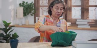 亚洲资深女性打开包装仙人掌从网上购物在家