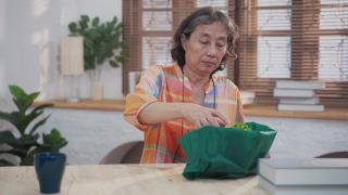 亚洲资深女性打开包装仙人掌从网上购物在家视频素材模板下载