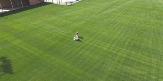 女孩们用手在足球场上除草。用草清理足球场。为赛季准备足球场