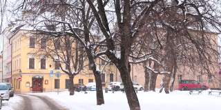 冬天，街上飘着雪花。车停在房子附近。布拉格都市生活。
