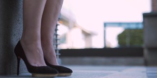 特写的女人的腿穿着优雅的高跟鞋在城市