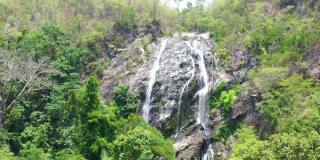 鸟瞰图的水从岩石悬崖从顶部向下到底部的绿色森林，4k