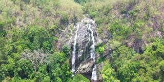 从鸟瞰图看，瀑布从森林中的岩石上倾泻而下。这是泰国的一个瀑布