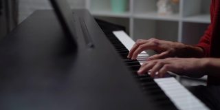 近距离的手，不认识的人在数字钢琴上演奏在家庭录音工作室。