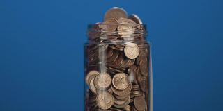旋转玻璃罐装满硬币和两欧元硬币与粘贴的加密投资文本蓝色背景的粘合剂注意