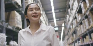 微笑的亚洲女人在购物中心或仓库散步快乐。女员工在工厂清点存货。购物业务概念