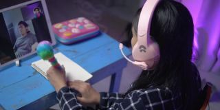 亚洲女学生在家里用数码平板电脑与老师进行视频通话，以Led灯为背景，社会距离的生活理念。