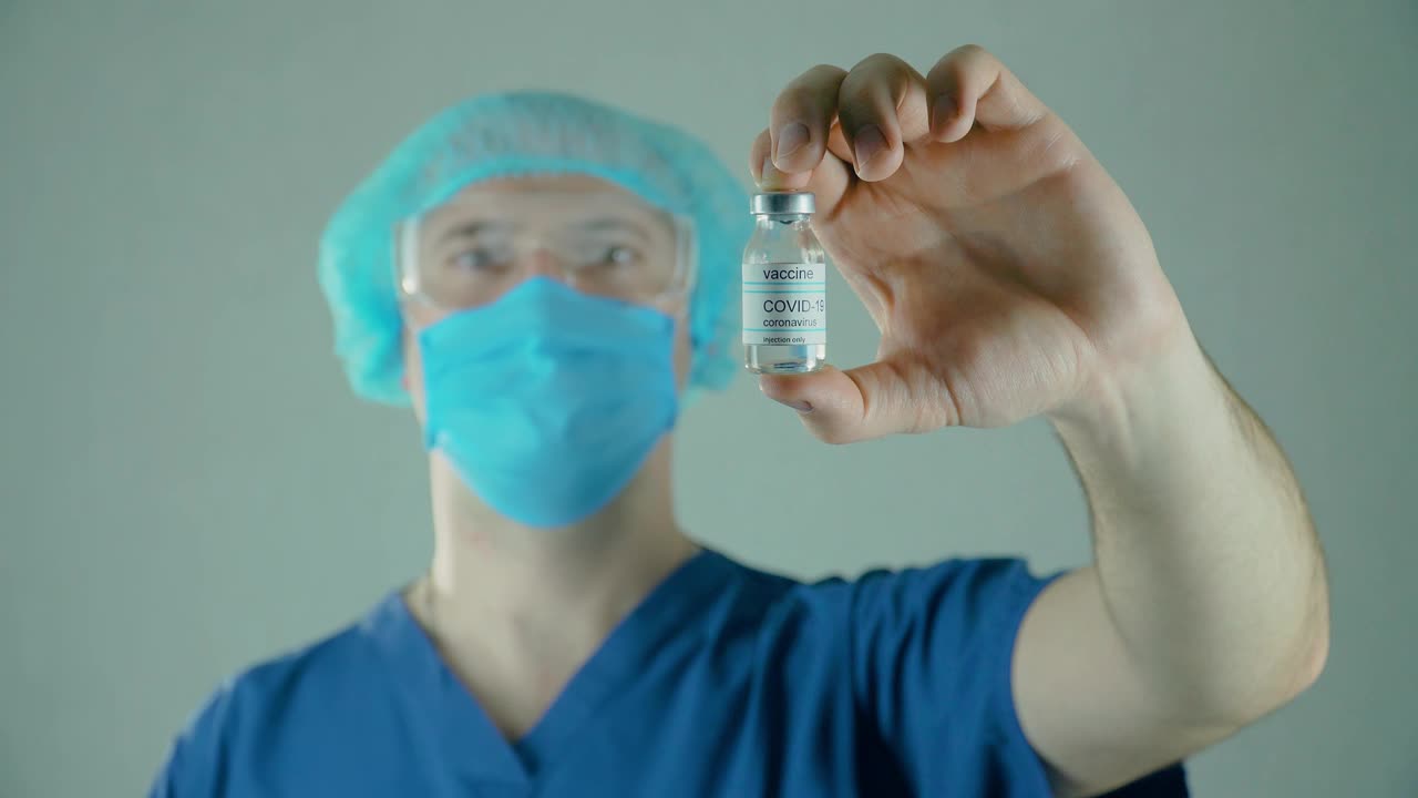 手持冠状病毒疫苗的男医生在医学实验室展示。安瓿或药瓶