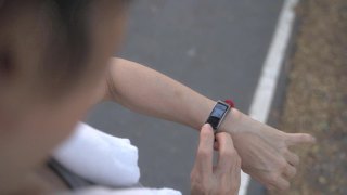 一名亚洲老年妇女在公园的树下触摸智能手表活动跟踪器。手指敲击运动手表卡路里和心率信息。慢动作轨道拍摄。医疗保健俯视图。视频素材模板下载