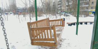 空荡的木制秋千长椅在冬天的时间里有雪。