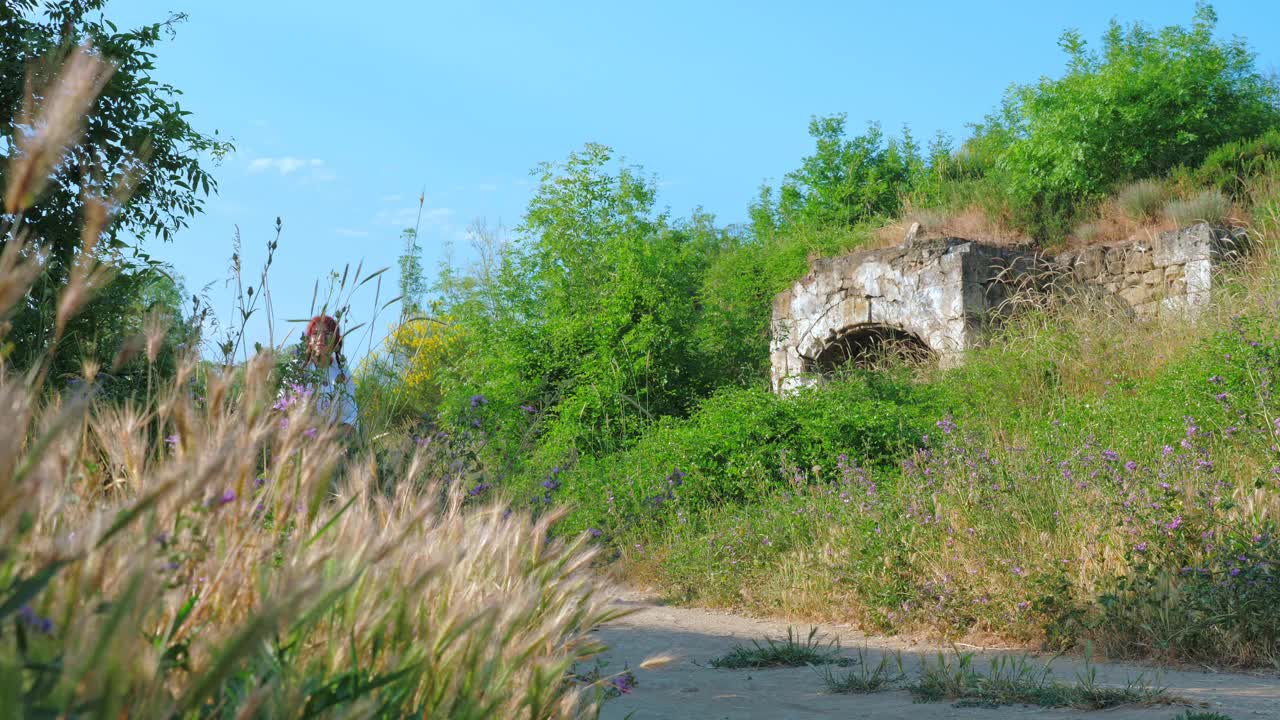 一个红头发的乡村女孩走在乡间的一条土路上。