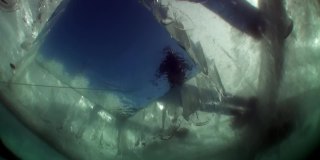 湖面冰洞附近的人们在冰下拍摄的水下视频。
