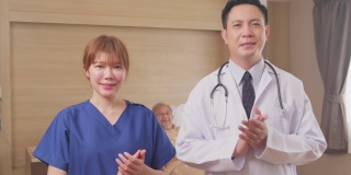 亚洲医生和护士微笑鼓掌鼓励病人的肖像。医疗队站在医院康复室的病床前。
