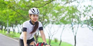 亚洲年轻美丽的女人骑自行车为健康在晚上在公共公园。运动员健康和坚定的女孩在运动服装锻炼通过自行车锻炼运动为她的健康健康。