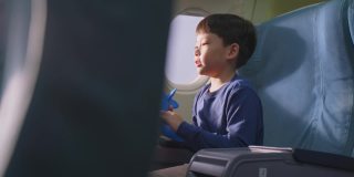 亚洲小男孩玩飞机模型玩具，坐在飞机上。这个孩子感到高兴和兴奋，想成为一名飞行员，作为他的梦想工作，当他长大后驾驶飞机。