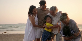4K多代亚洲家庭在夏日日落的海滩上一起放松和玩耍
