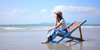 4K美丽的亚洲女人在海边的沙滩椅上休息。