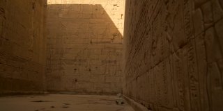 一个年轻人正在穿过Edfu寺和它美丽的象形墙壁。埃及。在尼罗河河畔的Edfu城附近的阿斯旺，希腊罗马建筑，献给荷鲁斯