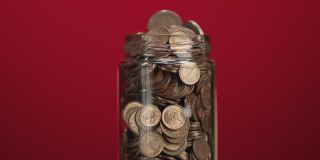 旋转玻璃罐装满硬币和两欧元硬币与粘贴的粘性纸条与加密投资文本在红色背景