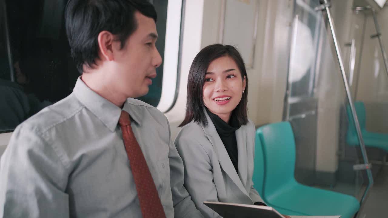 亚洲商人与女商人在空中列车或地铁上谈论他们的工作交通工具，人们的生活理念。