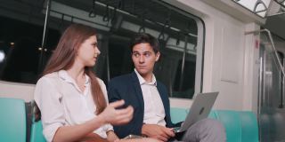 商人在空中列车或地铁上使用笔记本电脑与女商人交谈，他们的工作交通工具，人们的生活理念。