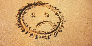 悲伤的笑脸在沙滩上被海浪改变。
