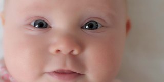 极端近距离的可爱的婴儿学步与完美的皮肤和蓝色的眼睛