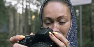游客在森林中拍摄风景。一名白人女子近距离射击。女孩用无反光镜单反相机拍摄视频。
