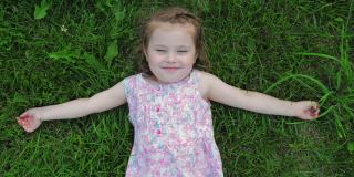 穿着裙子的可爱小女孩正微笑着躺在草坪上。