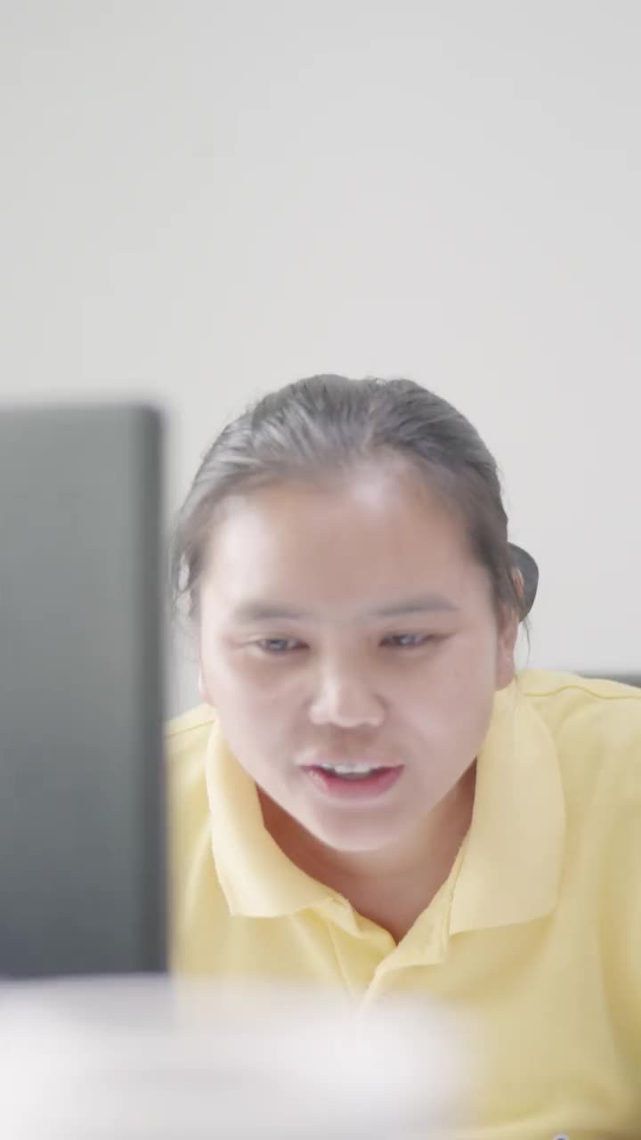 一位30-40岁的亚洲女商人穿着休闲装在她的办公室里使用电脑。