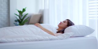 美丽迷人的亚洲女人在卧室的床上睡觉和甜蜜的梦在早上感觉如此放松和舒适，保健理念