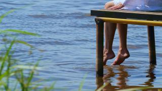 那个女孩坐在河边的一个木码头边上休息。视频素材模板下载