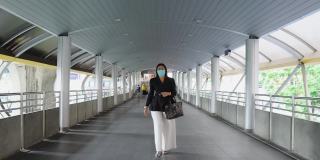 亚洲美丽的商业女性戴着防护面具走在城市的街道上。