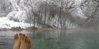奥地利卡林西亚的一个温泉池。湖被雪包围着。周围还有一片茂密的森林。泡沫在池塘上冒着蒸汽。水滴在水面上摆动。自然能源。冬季室外