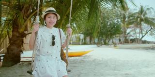 亚洲女性穿休闲服装幸福微笑放松休闲玩秋千与乐趣和退出享受假期夏季假日旅游概念