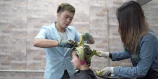 亚洲华人和印度理发师在美容院染发女顾客的头发。