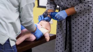 医疗人体模型娃娃紧急援助。对蹒跚学步的孩子进行急救培训。妇女手中的呼吸器放在一个孩子的假人身上。视频素材模板下载
