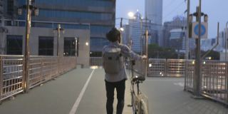 亚洲商人在立交桥上推自行车