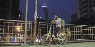 亚洲商人和他的自行车在立交桥和使用手机与现代建筑背景