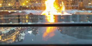 透过在街道上点燃的加热咖啡馆路人的保护玻璃，火焰的观点