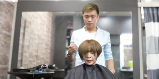 亚洲华人女顾客摇着她的头发，美发师为她做最后的造型。