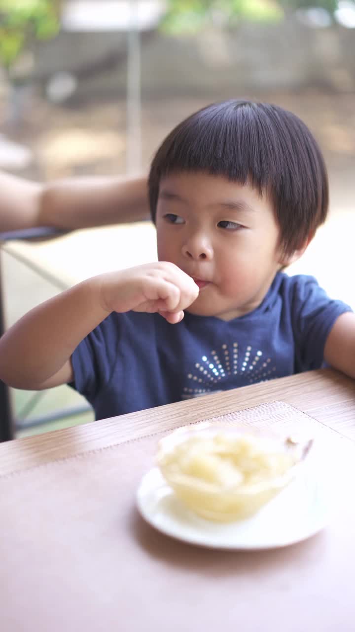 一个亚洲男婴和母亲在餐厅吃甜点的垂直镜头