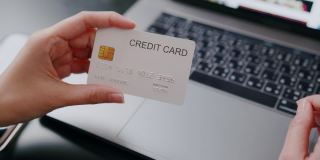 有魅力的女人拿着信用卡在网上付款，同时在笔记本电脑上网上购物